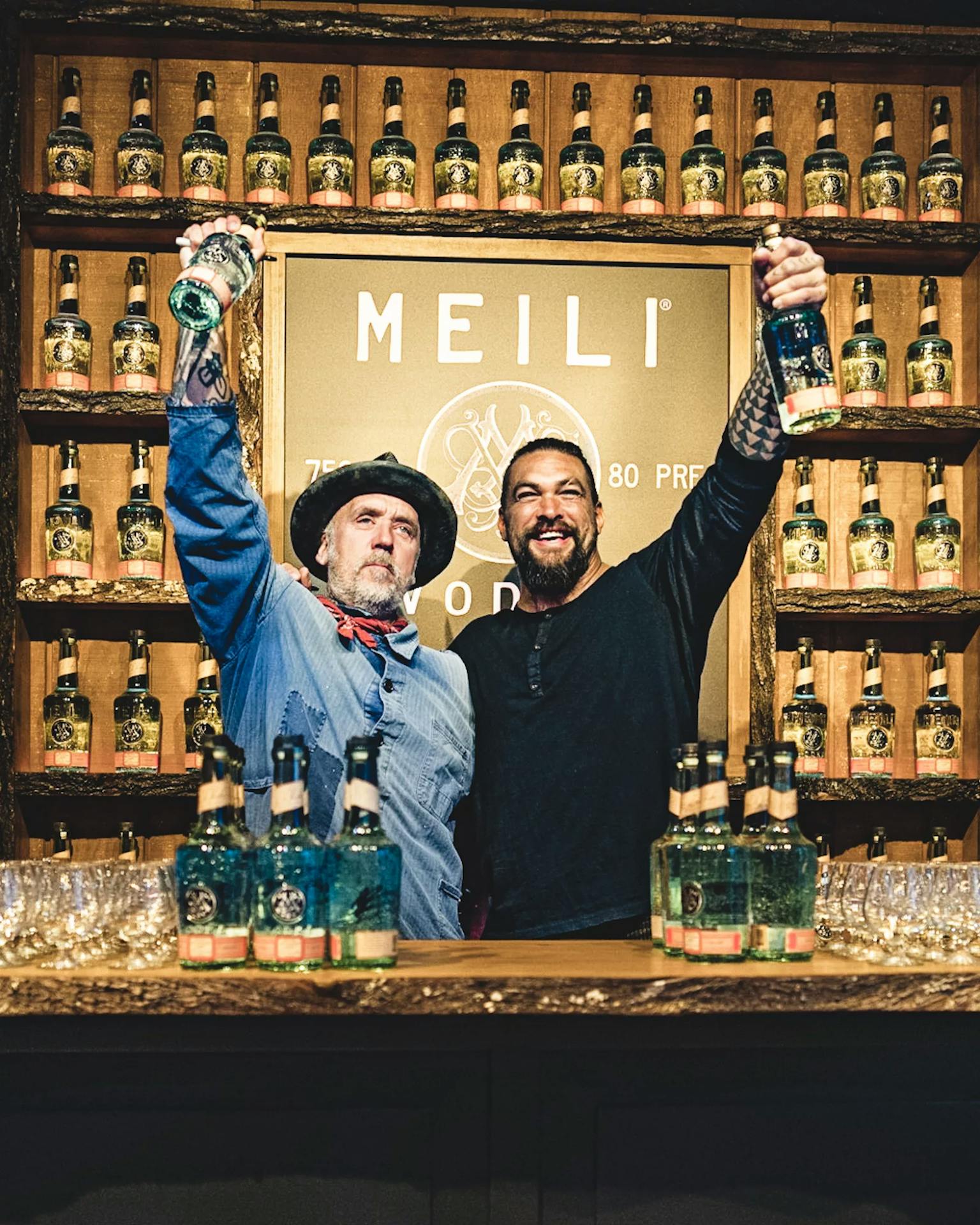 jason momoa and blaine halvorson holding vodka bottles with Meili in background
