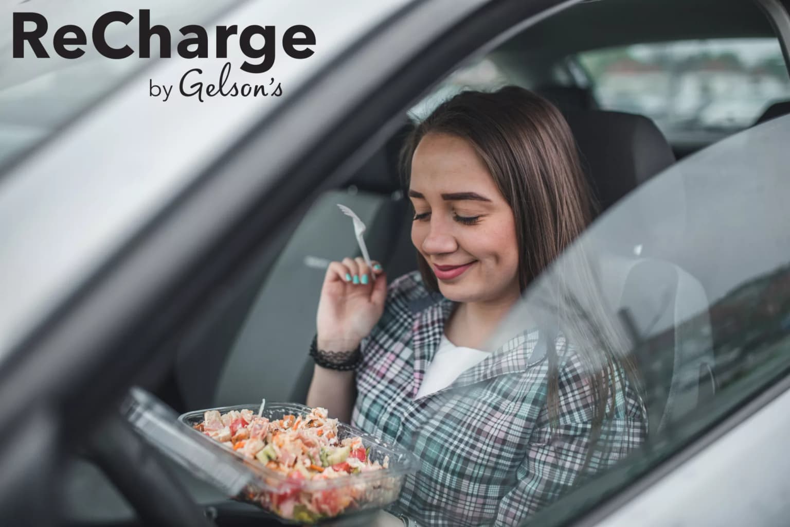 smiling woman in car eating a salad with ReCharge by Gelson's logo in black