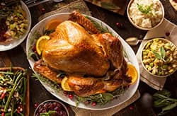 whole cooked turkey on platter surrounded by holiday sides.